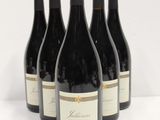 four bottles of wine are lined up on a white surface