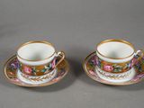two cups and saucers with floral designs are sitting on a table