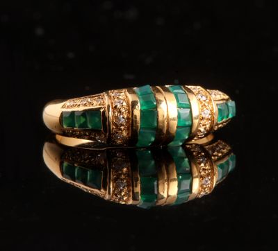 un gros plan d'une bague en or sertie de pierres vertes et de diamants