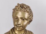 a gold statue of a boy holding a book