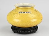 yellow vase with black base on white background with chinese writing on it