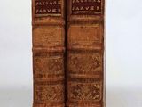 two old books are sitting side by side on a white surface