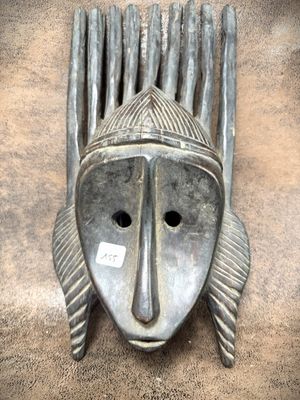 an image of a metal mask hanging on the side of a wall