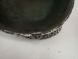 a silver bowl on a white table with a black background