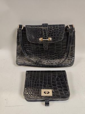 deux sacs à main en cuir d'alligator noir posés sur une surface blanche