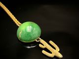 Collier plaqué or avec une pierre verte et un cactus sur fond noir
