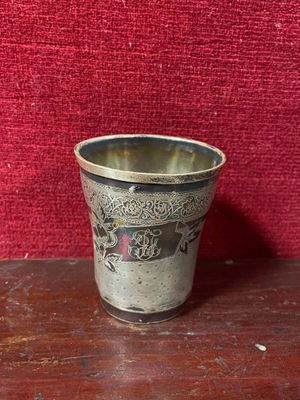 une coupe en argent posée sur une table en bois, sur fond rouge