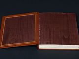 an open brown book sitting on top of a table next to a black background
