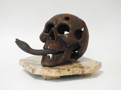 un crâne en bronze orné d'une longue corne, posé sur un socle en marbre