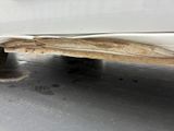 a white car with a dirty exhaust pipe on the side of it