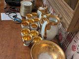a wooden table topped with gold dishes and cups