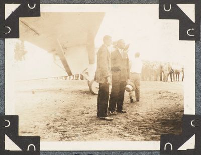 une photo en noir et blanc de deux hommes debout devant un avion