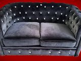une photo d'un canapé Chesterfield en velours noir aux accoudoirs cloutés