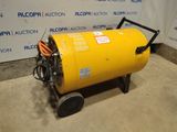 a large yellow barrel sitting on top of a cart in front of a wall