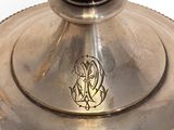 a silver plate with a candle on it on a white surface