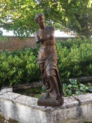 une statue représentant une femme debout sur un bloc de pierre