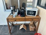 une table sur laquelle se trouvent un micro-ondes, une cafetière et d'autres objets