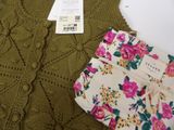 a green sweater with pink flowers on it next to a green sweater
