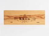 the wooden box is holding a bottle of wine and a wooden box with the word krug on it