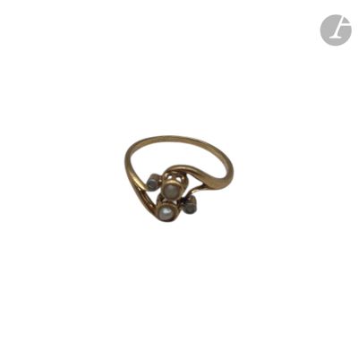un gros plan d'une bague en or ornée de perles sur fond blanc