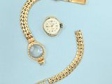 une montre en or et un bracelet sur un fond bleu