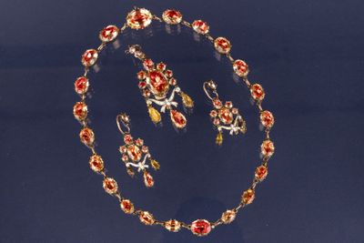 une photo d'un ensemble composé d'un collier et de boucles d'oreilles ornés de fleurs rouges et jaunes