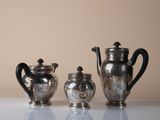 three silver teapots sitting on a white table