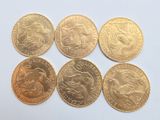 six types différents de pièces d'or posées sur une surface blanche