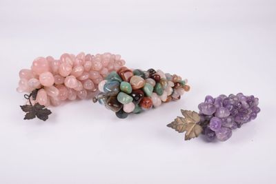 trois perles de couleurs différentes et une grappe de raisin sur un fond blanc