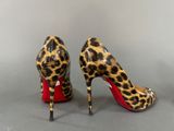 leopard print high heels with red soles on a grey surface