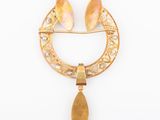 an image of a gold broochle with two leaves and a tear