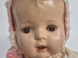 a baby doll with a pink dress and bonnet on