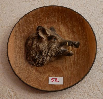 une image représentant une tête de sanglier fixée sur une plaque en bois