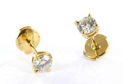 two pairs of diamond stud earrings on a white surface