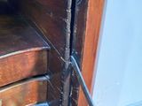 a cat that is sitting on the steps of a wooden cabinet