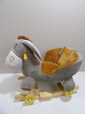 stuffed donkey sitting on a wooden sled with wheels on a white surface