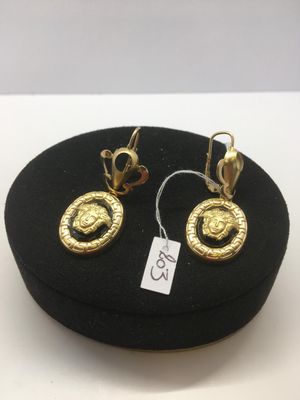 deux paires de boucles d'oreilles en or sur un chapeau noir muni d'une étiquette de prix