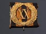 an image of a gold and black badge with a wreath on it
