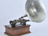 a silver gramphone on a wooden stand on a white background