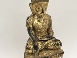 une statue en or représentant un Bouddha assis au sommet d'une pile de livres
