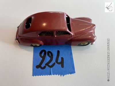 une petite voiture rouge ornée d'un ruban bleu, posée sur une table