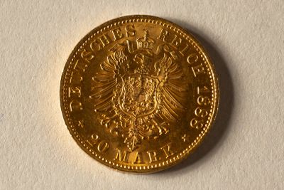 l'image d'une pièce d'or posée sur une surface blanche