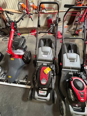 Plusieurs tondeuses à gazon sont alignées dans un garage