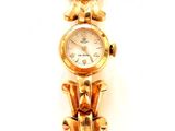 une montre-bracelet en or avec un cadran blanc sur fond blanc