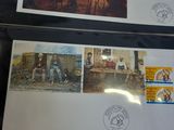 two framed pictures of people and animals on a table with stamps