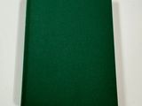 a green book sitting on top of a table next to a white wall