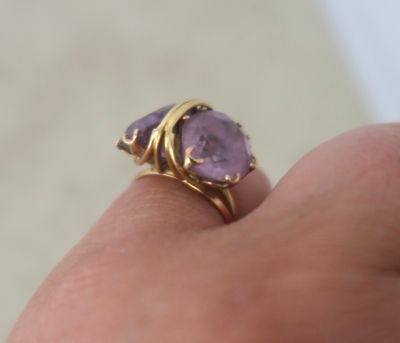 someone is holding a ring with a purple stone on it