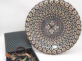 une assiette noire et blanche posée à côté d'une boîte à bijoux