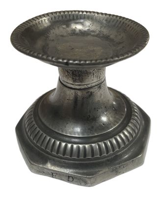 une assiette en argent posée sur un socle, sur fond blanc