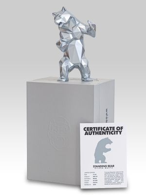 silver sculpture of a bear holding a baseball bat on top of a white box